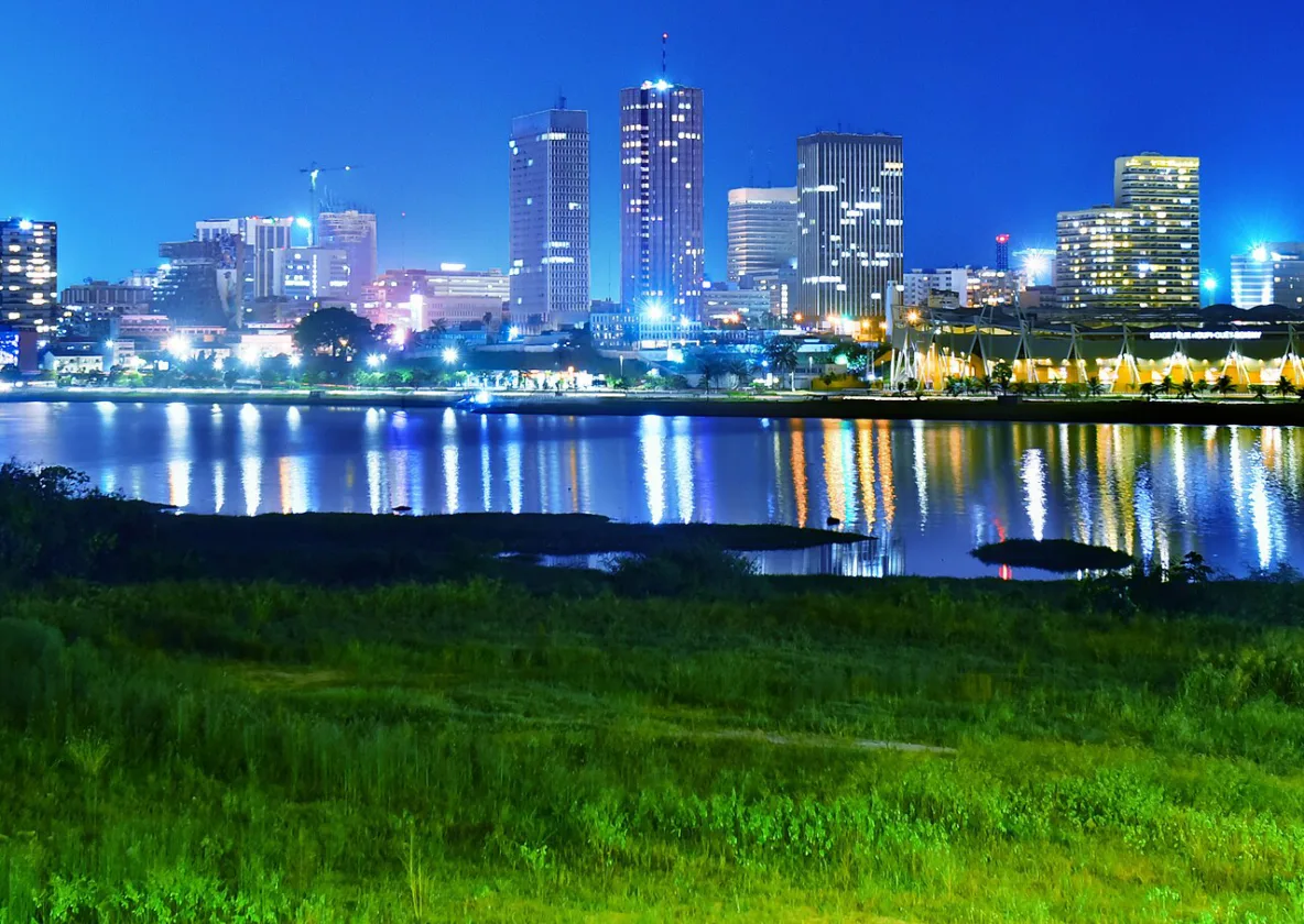 Les tours du Plateau à Abidjan, éclairées la nuit et reflétées dans la lagune.